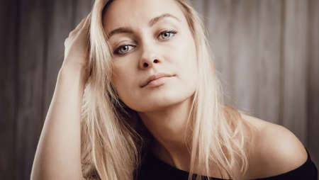 Happy beautiful young blond woman portrait with wooden backgroundの写真素材
