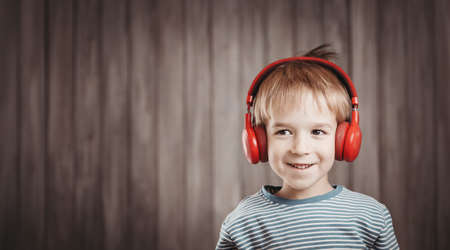 little boy on wooden background with red headphonesの写真素材