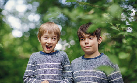 Two lovely brothers sitting in park with flowers huggingの写真素材