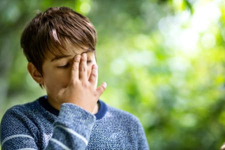 child with headache. Upset young boy outdoorsの写真素材