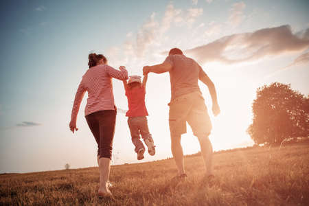 girl with mother and father holding hands on the natureの写真素材