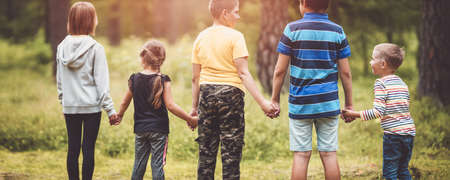 Boys and girls standing in the forest and holding hands on summer holidaysの写真素材