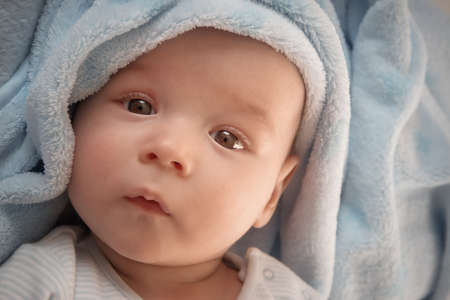 three month old baby wrapped in blue blanketの写真素材