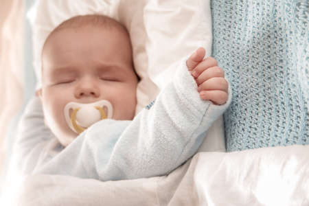 Baby sleeping covered with soft white blanketの写真素材