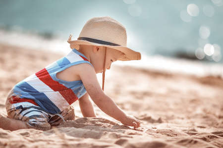 little boy playing at the beach in straw hatの写真素材