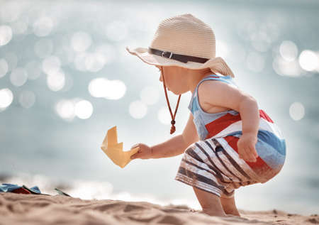 little boy playing at the beach in straw hatの写真素材