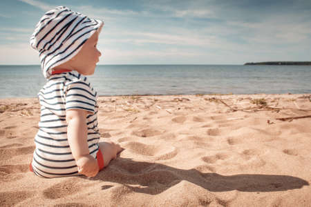 Little baby boy sitting on the beach in summer dayの写真素材