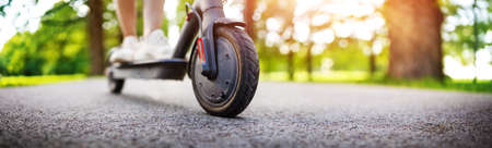 Woman riding on scooter in park in summerの写真素材