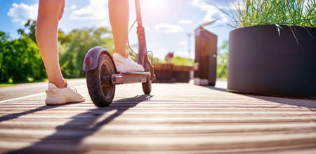 Woman riding on scooter in park in summer