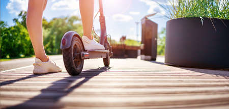 Woman riding on scooter in park in summerの写真素材