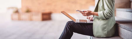 young woman with laptop sitting on the stairsの写真素材