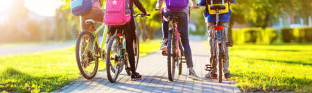 Children with rucksacks riding on bikes in the park near schoolの写真素材