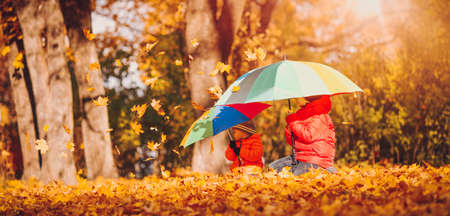 children with umbrellas in beautiful autumnal day. Boys playing outdoors in the parkの写真素材