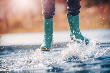Child walking in wellies in puddle on rainy weather. Boy under rain in summerの写真素材