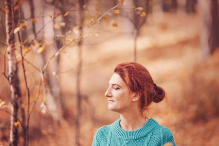 Pretty woman with red hair in autumn forest.の写真素材