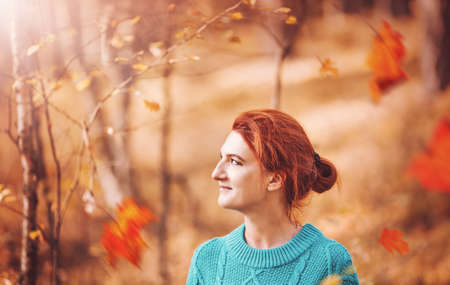 Pretty woman with red hair in autumn forest.の写真素材