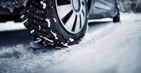 Closeup of the car tire on winter road covered with snowの写真素材