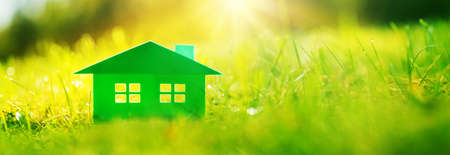 Green house on fresh grass on a sunny day. Model of a family housing standing on the meadow.の写真素材