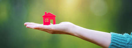 Model of small red house in the human hand. Concept of funding, buying, selling and renting.の写真素材