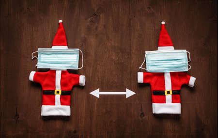 Santa clothes with a medical face mask on brown wooden background