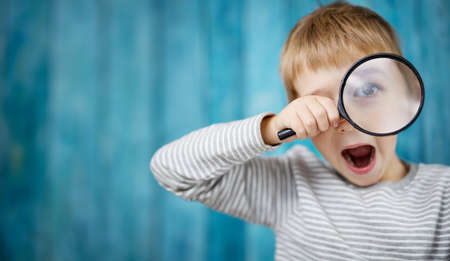 Little boy shocked looking through a magnifying glass