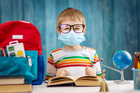 Boy in medical face protection mask indoors on blue backgroundの写真素材