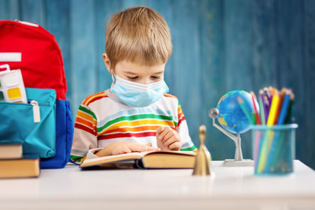 Boy in medical face protection mask indoors on blue backgroundの写真素材
