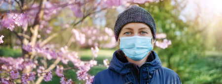 young woman in medical face protection mask outdoors in nature