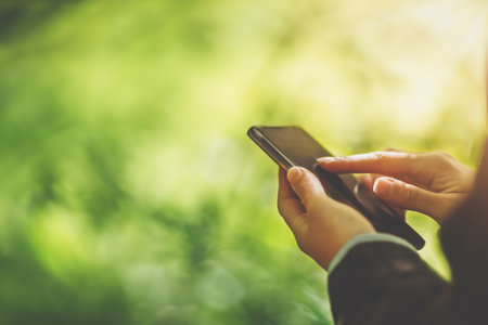 Young woman on nature using her smartphoneの写真素材