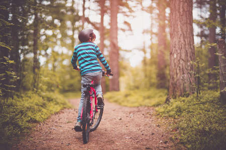 Child on a bicycle in the forest in early morningの写真素材