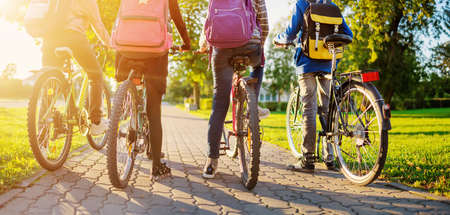 Children with rucksacks riding on bikes in the park near schoolの写真素材