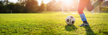 Child playing football on the field with gates.の写真素材