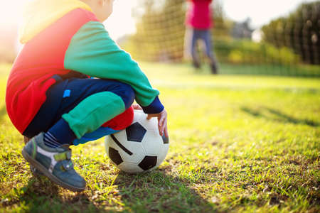 Children playing football on the field with gates.の写真素材