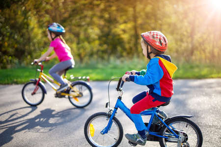 Cute children riding on bicycles on asphalt road in summer.の写真素材