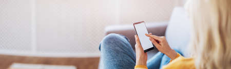 Young woman on the couch using her smartphone.の写真素材