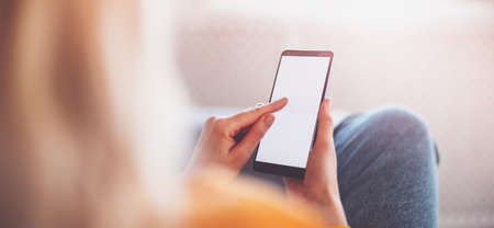 Young woman on the couch using her smartphone.の写真素材