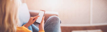 Young woman on the couch using her smartphone.の写真素材