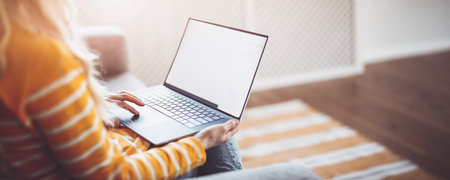 Young woman with laptop sitting on the sofa in living room.の写真素材