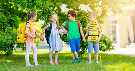 Cute children with rucksacks standing in the park near the schoolの写真素材