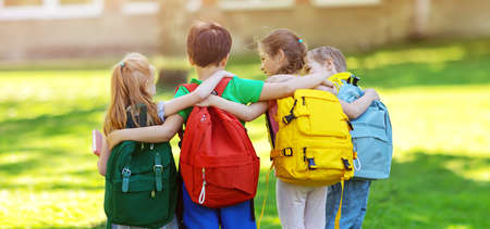 Group of children with rucksacks standing in the park near the schoolの写真素材