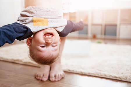 Mother holding upside down her laughing child.の写真素材