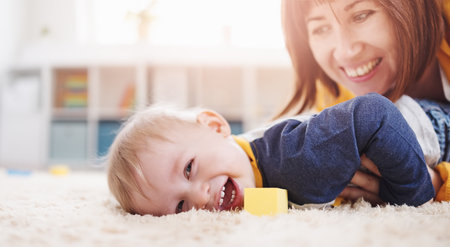 Mother playing with her cute son on the floorの写真素材