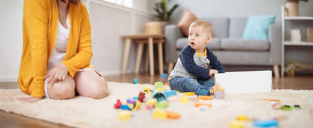 Mother playing with her cute son on the floorの写真素材
