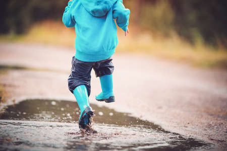 Child walking in wellies in puddle on rainy weatherの写真素材