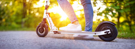 Woman riding on scooter in park in summerの写真素材