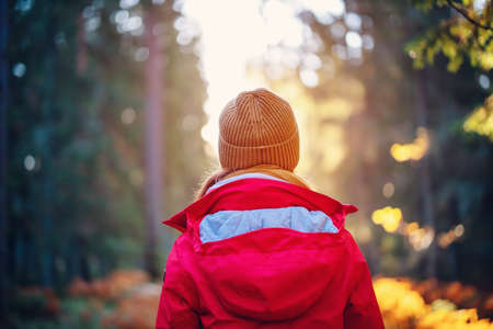 Young woman alone in the autumnal forest in sunrise.