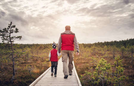 Father with son walking on the path on the Estonian bogs.の写真素材