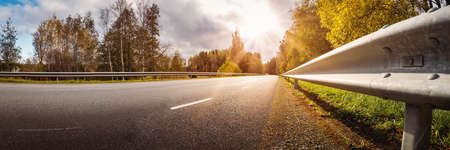 Beautiful panorama of the road and autumnal trees on the both sides of it.の写真素材