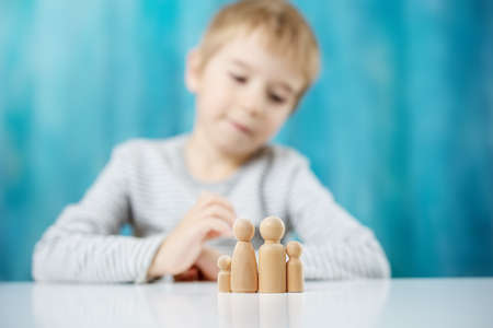 Child with wooden figures of the family on the blue backgroundの写真素材