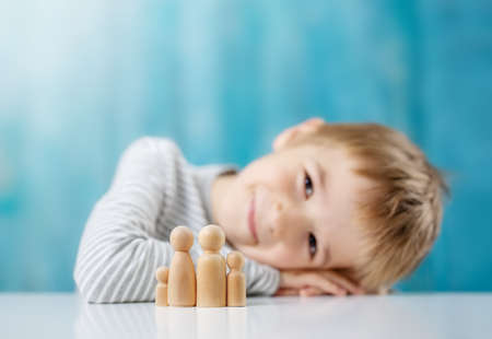 Smiling child with wooden figures of the family on the blue backgroundの写真素材